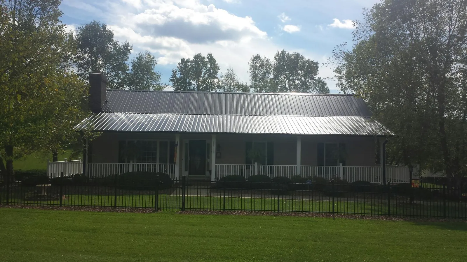 Gray metal roof on a brick ranch with a full width front porch — Gutter Guard Installation work by our crew in Westville