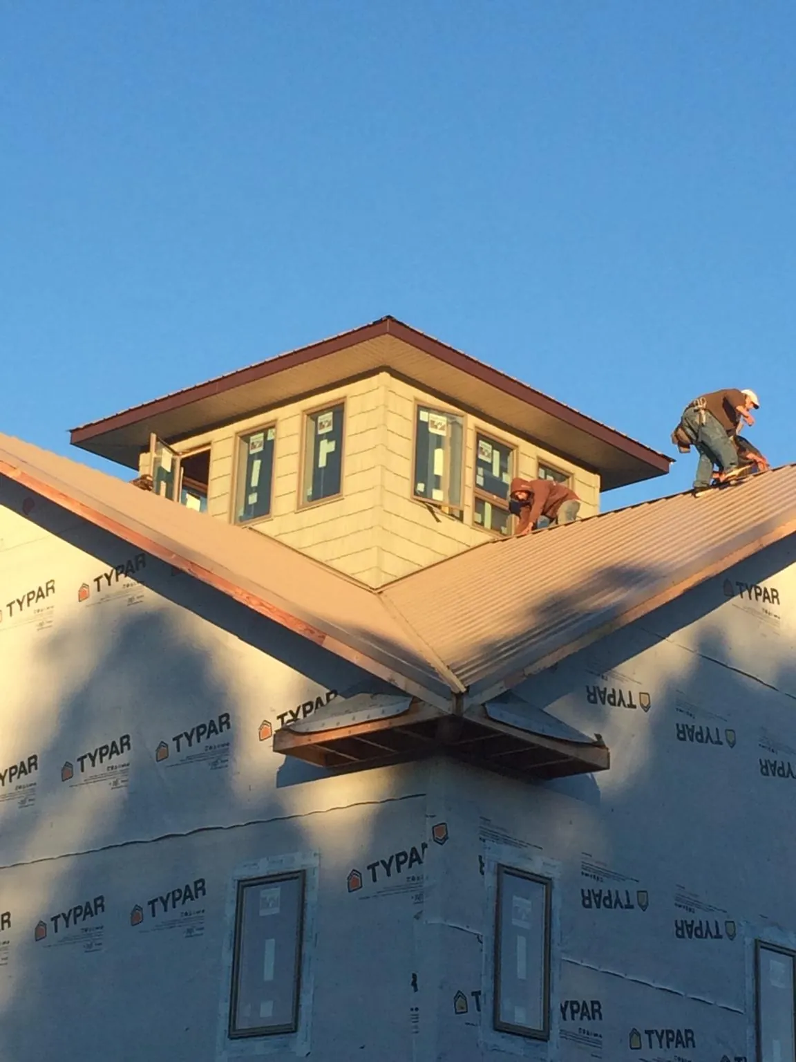 Roofers working around a rooftop cupola on a new metal roof at sunset — Roof Waterproofing in Westville by Roofing Brothers